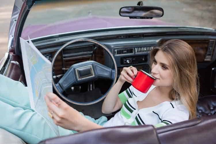 A girl drinking from a red cup in a convertible car