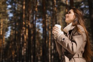 Woman drinking coffee in the woods