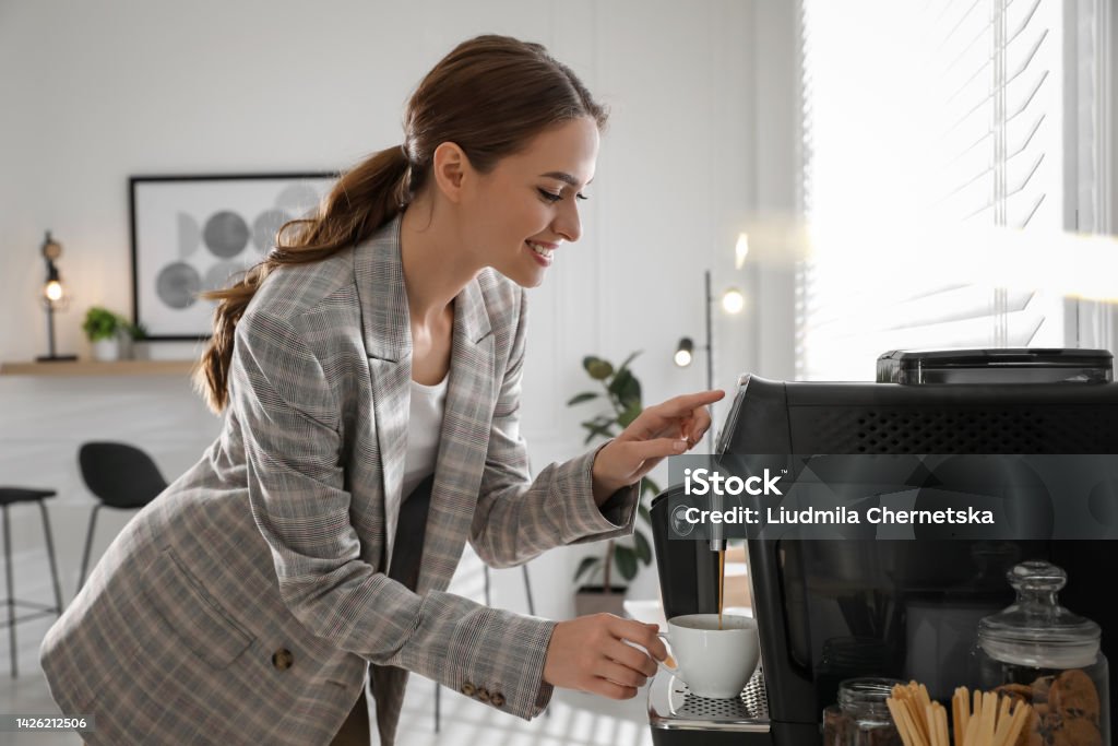 Young woman making coffee before leaving for work